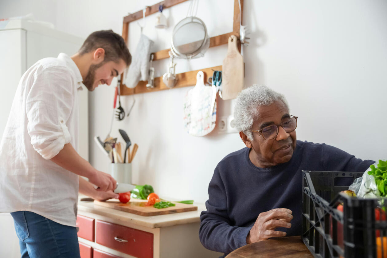 Picture of an elderly man and his male care giver cooking.